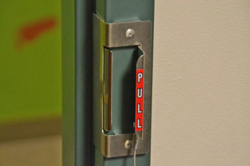 Image of Safe-Latch fast lockdown device in use on in-swing classroom door or office door.